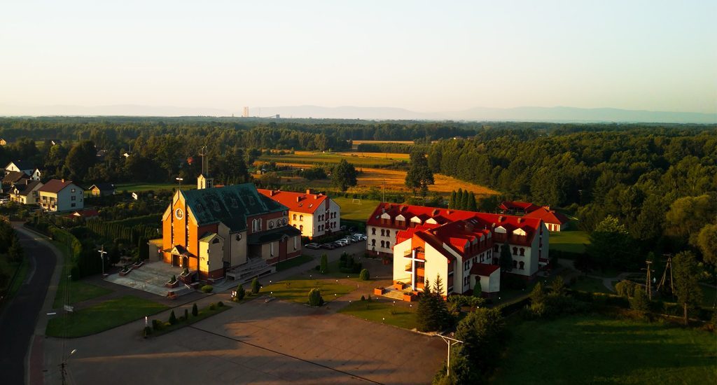 Widok z lotu ptaka na Centrum św. Maksymiliana w Harmężach, kościół i budynki klasztorne otoczone polami i lasami